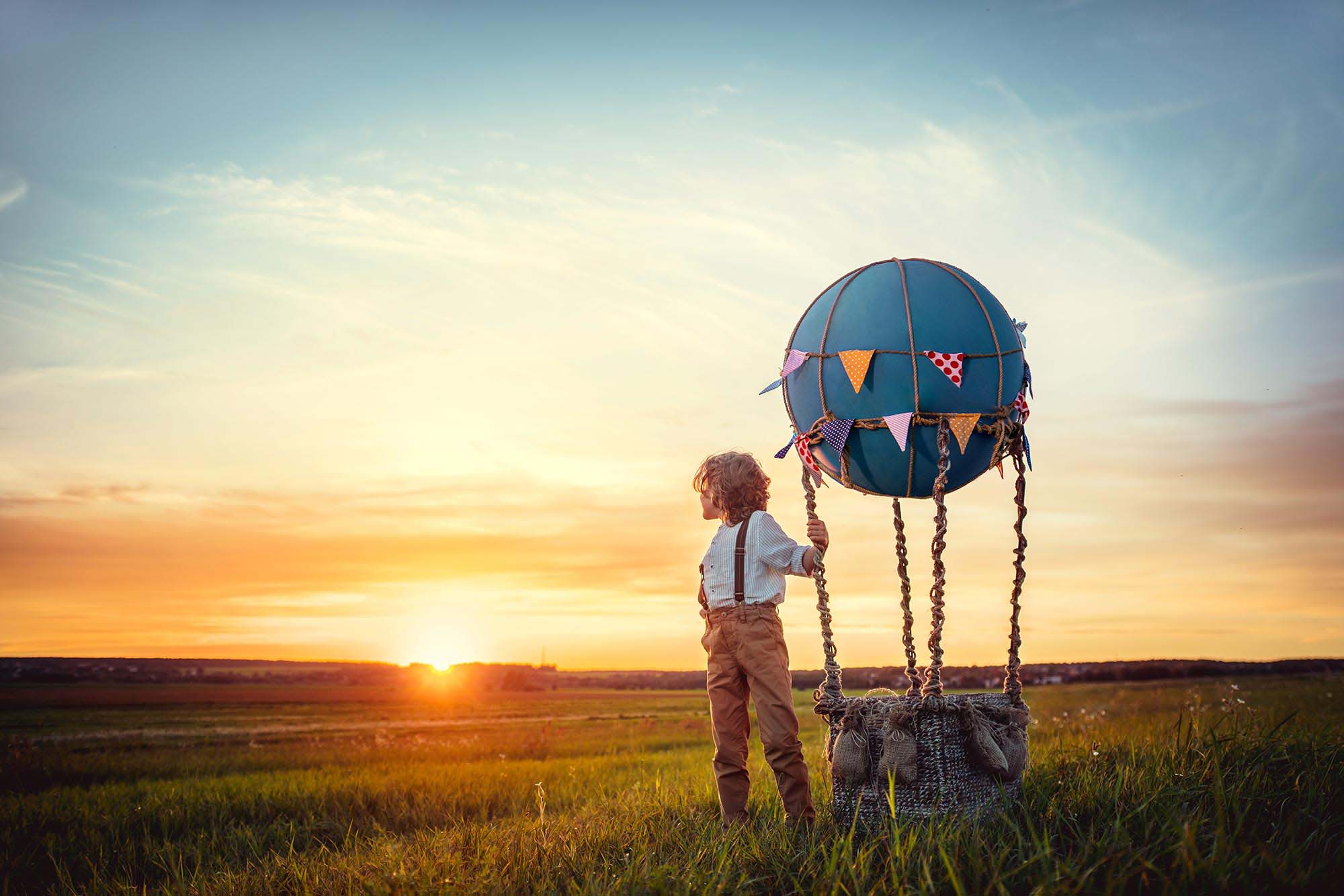 Travel management – a boy with air balloon looking into the sunset – wanderlust